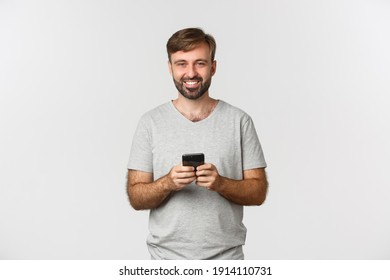 Portrait Of Happy Smiling Man With Beard, Wearing T-shirt, Using Mobile Phone, Standing Over White Background