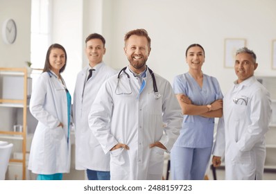 Portrait of a happy and smiling man doctor or nurse standing with group of a healthcare staff in a hospital setting. Professional medical team exemplifies unity and expertise in clinic care. - Powered by Shutterstock