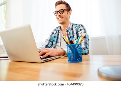 Portrait of happy smiling man in glasses working with laptop