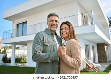 Portrait of happy smiling mature older family couple new property buyers modern dream luxury villa owners standing outside house, affectionate senior middle aged man and woman in love hugging outdoor. - Powered by Shutterstock