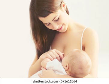 Portrait happy smiling mother feeding breast her baby at home in white room