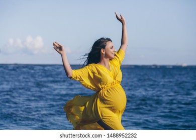 Portrait of happy smiling pregnant woman in yellow dress walking and relaxing on the beach at summer
 - Powered by Shutterstock