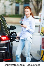 Portrait Happy Smiling Pretty, Attractive Woman Filling Compact Car Tank With Petrol At Gas Station Isolated City Background. Oil Prices Economy, Energy Cost, Transportation Industry, Travel, Concept 