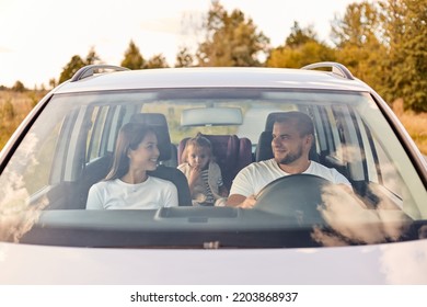 Portrait Of Happy Smiling Satisfied Family Traveling In Car With Their Child On Back Seat, Talking And Laughing, Expressing Positive Emotions, Riding Automobile.