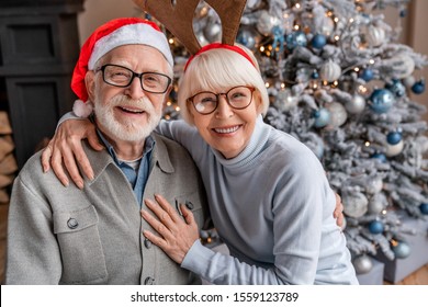 Portrait of happy smiling senior couple in santa hats celebrating at home - Powered by Shutterstock