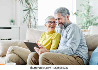 portrait of happy smiling senior couple using tablet at home - Powered by Shutterstock