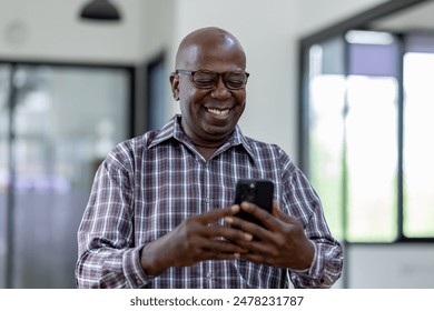 Portrait of happy smiling senior man sitting on desk at cafe using smartphone and laptop - Powered by Shutterstock