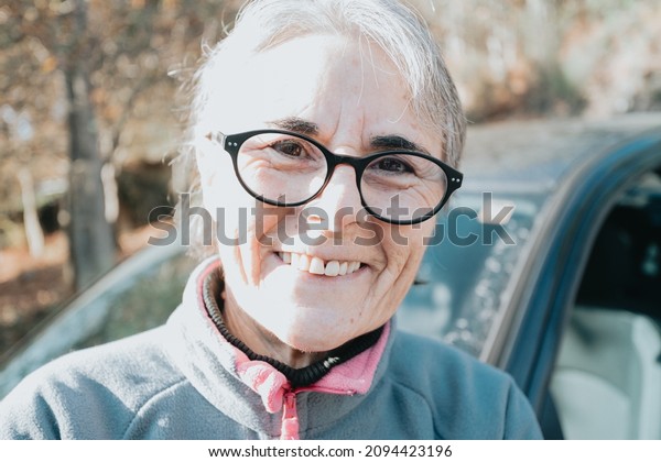 Portrait of a happy smiling senior woman outside\
car learning to drive a car. Safety drive. Learning new hobby,\
habit and skill for this new year. Elderly person approving the\
driving license.