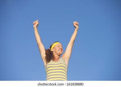 Portrait Happy Smiling Successful Active Attractive Mature Woman In Winner Pose, Sporty, Healthy, Fit, Arms Up, Blue Sky Background, Copy Space.