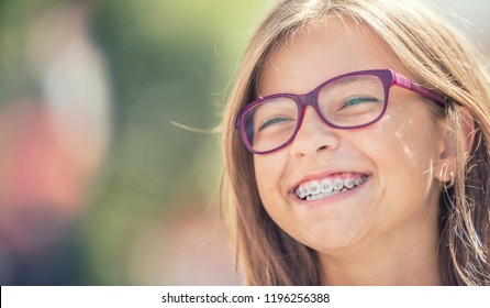 Portrait of a happy smiling teenage girl with dental braces and glasses.