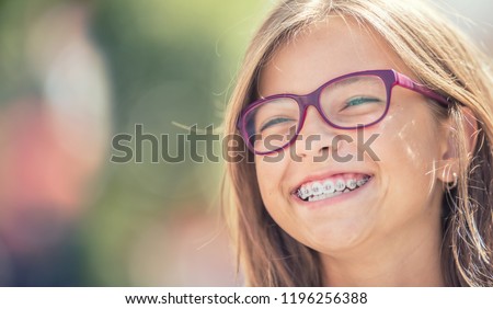 Portrait of a happy smiling teenage girl with dental braces and glasses.
