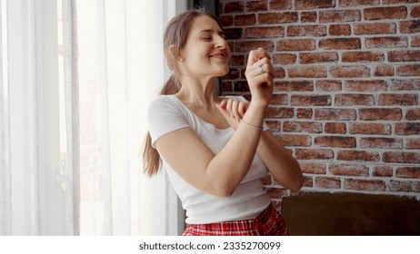 Portrait of happy smiling woman dancing in living room against brick wall. People relaxing at home, having fun, positive emotions and joy - Powered by Shutterstock