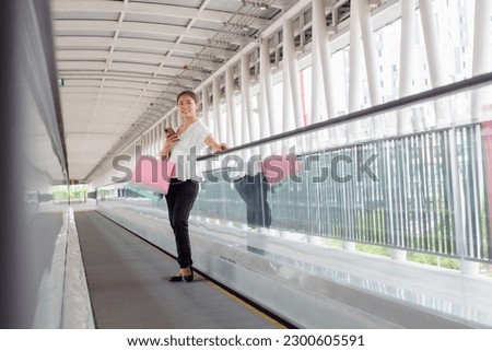 Portrait of happy smiling woman with shopping bags in corridor walk way. Beautiful woman with a paper bag.