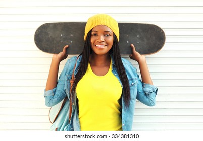 Portrait of happy smiling young african woman model posing with skateboard in colorful clothes in the city - Powered by Shutterstock