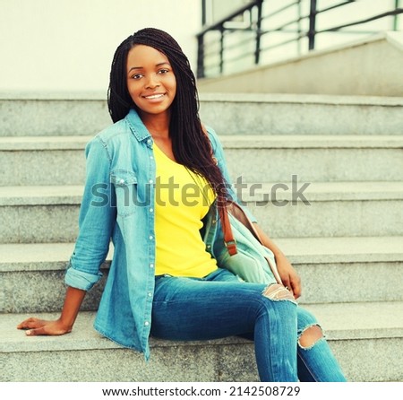 Portrait of happy smiling young african woman in casual in the city