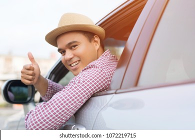 Portrait Of Happy Smiling Young Asian Man Traveler On The Road Showing Thumbs Up While Driving In His Car.