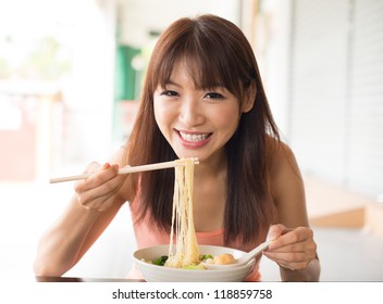 Portrait Of Happy Smiling Young Asian Woman Eating Asian Noodles