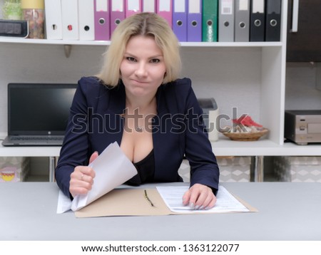 Portrait of happy smiling young cheerful businesswoman sitting in office. Success in business concept studio shot talking to a client. Blue suit. Female model. Gray wall background. Looking at camera.