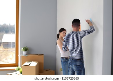 Portrait of happy smiling young couple painting interior wall of new house. young couple - Shutterstock ID 1158725665