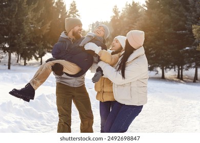 Portrait of happy smiling young family with son and daughter standing outdoors enjoying time together in winter forest. Mother, father with two kids walking outside. Family leisure concept. - Powered by Shutterstock