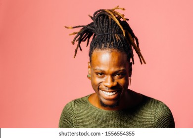 Portrait of a happy, smiling  young man in with cool dreadlocks hairstyle looking at camera, isolated on pink	