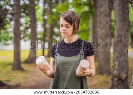 Portrait of happy smiling young woman comparing thermo cup or tumbler with disposable paper coffee cup Stock photo © 