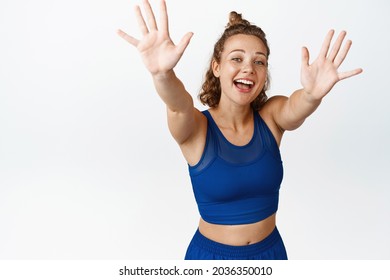 Portrait Of Happy Sportswoman Waving Hands To Say Hello, Smiling And Saluting While Wearing Fitness Clothes, Saying Hi To Fitness People, White Background.