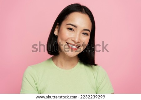 Portrait of happy successful asian woman standing, looking at camera with charming smile. Indoor studio shot isolated on pink background 