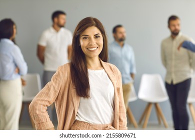 Portrait Of Happy Successful Attractive Businesswoman And Professional Business Coach. Smiling Good Looking Young White Woman In Smart Casual Peach Color Suit Standing Against Blurred Office Backdrop