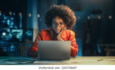 Portrait of a Happy Successful Businesswoman Using Laptop Computer in Creative Agency in the Evening. Black Female Smiling while Browsing Internet, Checking Funny Memes on Social Media Network. - Shutterstock ID 2231746647