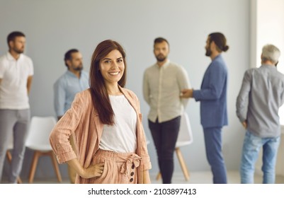 Portrait Of Happy Successful Confident Businesswoman. Young Business Woman Or Team Leader In Elegant Smart Casual Outfit Looking At Camera And Smiling Standing Hand On Hip Against Office Background