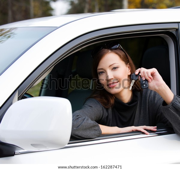 Portrait of happy successful woman with keys from the\
new car - outdoors 