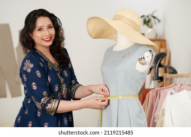 Portrait of happy tailor measuring dress on mannequin when double check everything before meeting client in her studio - Shutterstock ID 2119215485