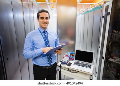 Portrait of happy technician holding clipboard in server room - Powered by Shutterstock