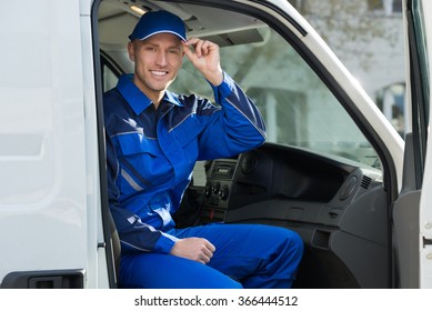 Portrait of happy technician in protective workwear sitting inside van
