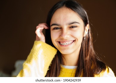 Portrait Of A Happy Teen Girl With Braces And Some Acne Smiling At Home With The Sun Coming Through The Window 