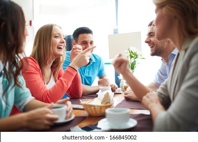 Portrait Of Happy Teenage Friends Sitting And Chatting In Cafe