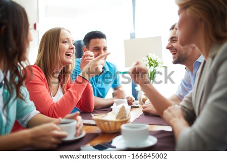 Portrait of happy teenage friends sitting and chatting in cafe