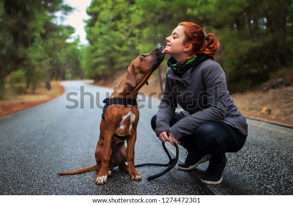 幸せな10代の女の子とローデシアン リッジバック犬のポートレート 女の子に甘いキスをする犬は舐めなさい 愛する動物は私のペットを愛している の写真素材 今すぐ編集