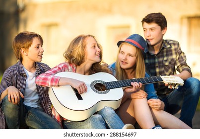 Portrait of happy teens playing the guitar surrounded by  friends - Powered by Shutterstock