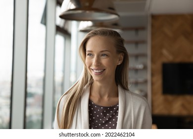 Portrait of happy thoughtful young business woman, leader, entrepreneur with toothy smile in casual looking at window away in good thoughts, imagining successful career or company future. Head shot