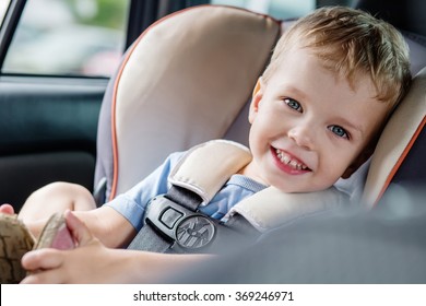 portrait happy toddler boy sitting in the car seat