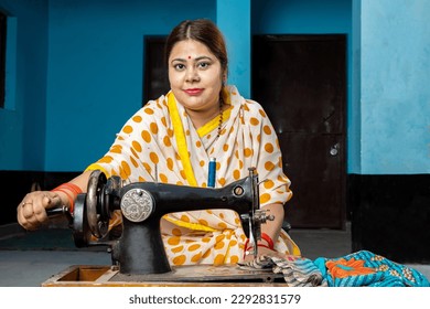 Portrait happy traditional indian woman housewife wearing sari using sewing machine at home. Skill india Concept.