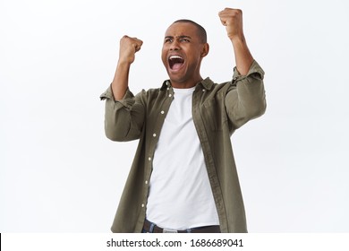 Portrait of happy, triumphing african-american man celebrating victory, football fan winning bet in sports game, raising hands up cheerful, rooting for team, achieve success, white background