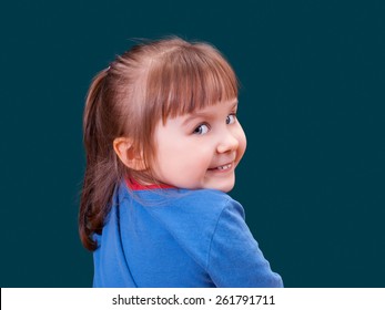 Portrait Of Happy Turning Around And Smiling Little Girl On Dark Green Background. Cheerful Kid.