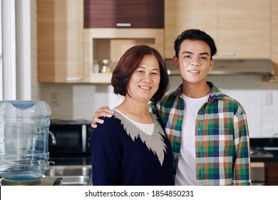 Portrait of happy Vietnamese mature woman and her teenage son smiling and looking at camera