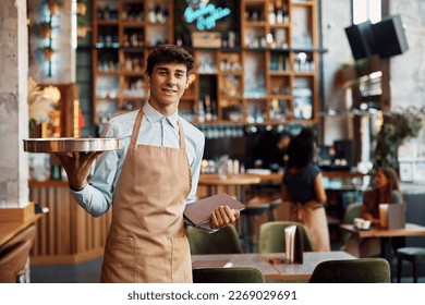Portrait of happy waiter in a cafe looking at camera. Copy space.