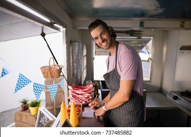 Portrait of happy waiter writing in notepad at food truck counter - Powered by Shutterstock