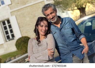 Portrait Of Happy Wealthy Middle Age Couple Outside Of Their House