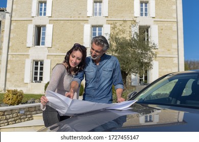 Portrait Of Happy Wealthy Middle Age Couple Studying A New Architecture  Project For Their House